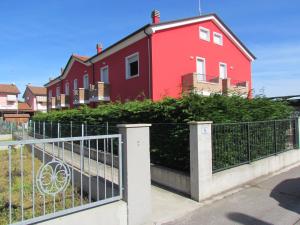 a red house with a fence in front of it at Siviero Apartments in Scardovari