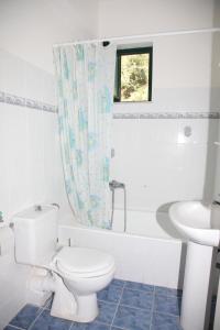 a white bathroom with a toilet and a sink at Villa Elena in Lixouri +26 photos