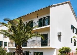 a white building with a palm tree in front of it at Apartmani AMI in Podstrana