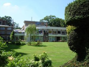un bâtiment avec une grande pelouse devant lui dans l'établissement Fletcher Parkhotel Val Monte, à Berg en Dal