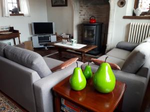 a living room with two couches and a table with green fruit at De Perelaar in Jabbeke