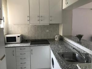 a kitchen with white cabinets and a sink and a microwave at Tropic Mar 2H in Benidorm