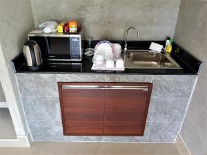 a small kitchen with a microwave and a sink at Sea Smile Resort in Prachuap Khiri Khan