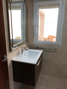 a bathroom with a white sink and a window at the Beach House in A Pobra do Caramiñal