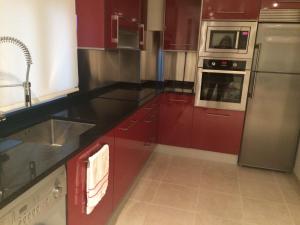 a kitchen with red cabinets and stainless steel appliances at the Beach House in A Pobra do Caramiñal
