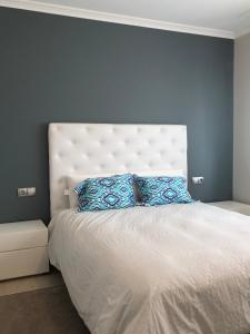 a bedroom with a large white bed with blue pillows at the Beach House in A Pobra do Caramiñal