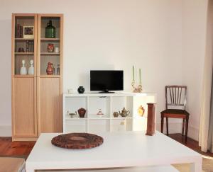 uma sala de estar com uma televisão num armário branco em Casa da Varanda Simpática em Lisboa