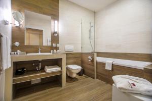 a bathroom with a sink and a toilet and a mirror at Mamaison Hotel Andrassy Budapest in Budapest