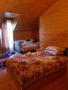 ブランにあるPension Bran Ioanaの木造キャビン内のベッド2台が備わる部屋
