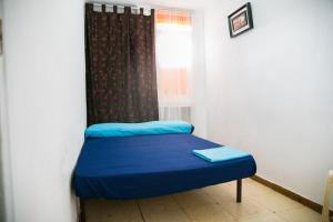 Mały pokój z niebieskim łóżkiem i oknem w obiekcie Habitaciones cerca del mar w mieście Reus