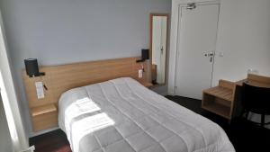a bedroom with a large white bed and a desk at Hotel Rivoli in Paris