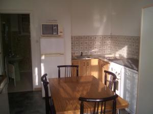a kitchen with a wooden table with chairs and a microwave at Le Gîte de Réaumur in Réaumur