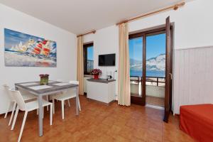 Zimmer mit einem Tisch, Stühlen und einem TV in der Unterkunft Residence Mariù in Malcesine