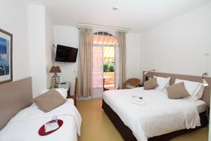 a hotel room with two beds and a window at Logis Hotel l'Esterella in Agay - Saint Raphael