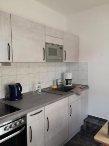 a kitchen with white cabinets and a sink and a microwave at Ferienwohnung Lilly in Wittenberge