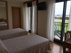 um quarto com 2 camas e uma grande janela em Hostal Santa Baia em Ribadumia