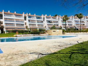 - un grand bâtiment avec une piscine en face dans l'établissement Apartamentos Jardines del Puerto Altamar, à Alcossebre