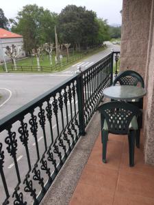 a table and chair on a balcony with a street at Hostal Santa Baia in Ribadumia