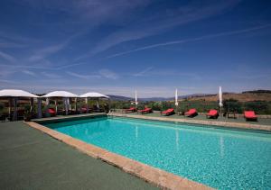 a swimming pool with red chairs and umbrellas at Quinta da Barroca Douro Valley in Armamar