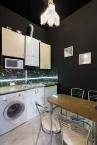 eine Küche mit einer Waschmaschine und einem Tisch mit Stühlen in der Unterkunft Austrian Apartments in Lwiw