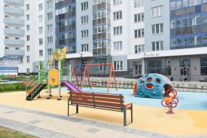 a playground with slides and a bench in front of a building at СелимВсех на Куйбышева in Yekaterinburg