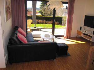 sala de estar con sofá negro y mesa en Panorama-Übernachtungen en Biberach-Ummendorf