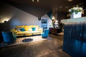 - un salon avec un canapé jaune et des fauteuils bleus dans l'établissement Hotel Ristorante Eurossola, à Domodossola