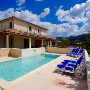 une piscine avec des chaises longues et une maison dans l'établissement Villa Vallon Pont d'Arc, à Vallon-Pont-dʼArc