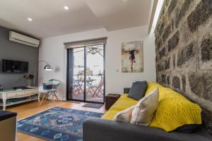 een woonkamer met een bank en een gele deken bij Chez Lúcia in Ponta Delgada