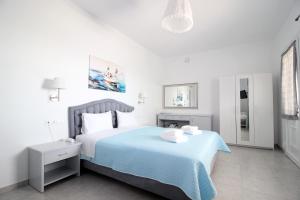a white bedroom with a bed with a blue blanket at Villa Oceania in Tourlos