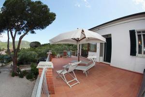 a patio with two chairs and an umbrella at Villa La Pila Bilo in Marina di Campo