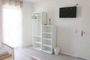 a white book shelf in a room with a tv at Dornfelder in Hanhofen