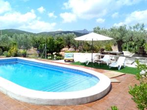 a swimming pool with a table and chairs and an umbrella at Casa Mariano in Rasquera