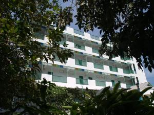 un edificio de apartamentos blanco con árboles delante de él en Makmai Villa - Rayong, en Ban Phe