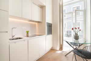 eine Küche mit weißen Schränken und einem Glastisch in der Unterkunft Lisbon Rouge Apartment in the Lisbon Heart in Lissabon