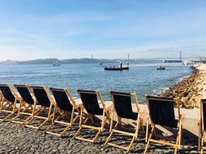 a row of chairs sitting on a beach next to the water at Lisbon Rouge Apartment in the Lisbon Heart in Lisbon