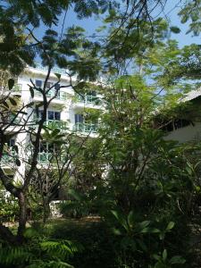 un edificio blanco con árboles delante de él en Makmai Villa - Rayong, en Ban Phe