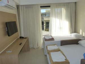 a bedroom with two beds and a tv and a window at Aldeia das Águas Park Resort - Flat Quartier in Barra do Piraí