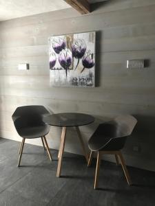 einen Tisch und zwei Stühle in einem Zimmer mit einem Gemälde in der Unterkunft Charly Studio In Gstaad in Gstaad