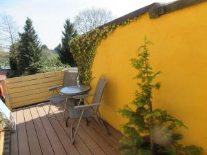 a yellow wall with a table and chairs on a deck at Ferienwohnung Sommer in Friedrichsbrunn