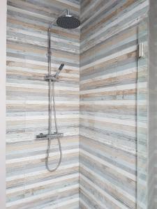 a bathroom with a shower with a wooden wall at 't Zandmanneke in Ostend