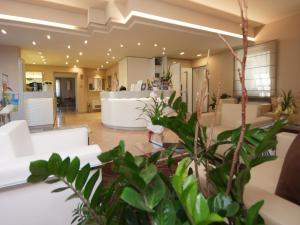 a lobby with white chairs and plants at Hotel Dori in Peschiera del Garda