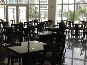 un comedor con mesas, sillas y ventanas en Costa do Mar Hotel, en Fortaleza