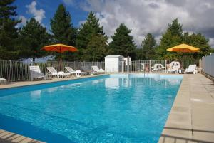 a swimming pool with chairs and umbrellas on a fence at Camping Le Domaine Des Jonquilles in Saint-Alban