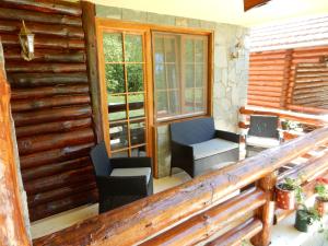 a porch of a log cabin with chairs and windows at Apartments Izvor Lisine in Strmosten