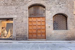 ein Backsteingebäude mit einer Holztür und zwei Fenstern in der Unterkunft Finardi Apartment in Florenz