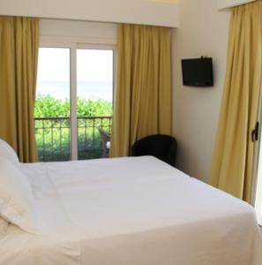 1 dormitorio con cama blanca y balcón en Mouria Pension Rooms & Studios, en Palaia Epidavros