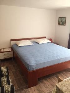 Schlafzimmer mit einem Bett mit blauer Bettwäsche und Kissen in der Unterkunft Apartments Bili in Starigrad-Paklenica