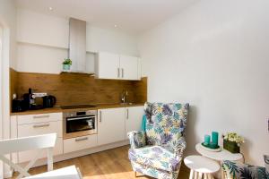 a kitchen with white cabinets and a chair in it at Lou-Lou in Zandvoort