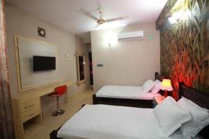 a hotel room with two beds and a flat screen tv at Little Rangpur Inn in Rangpur